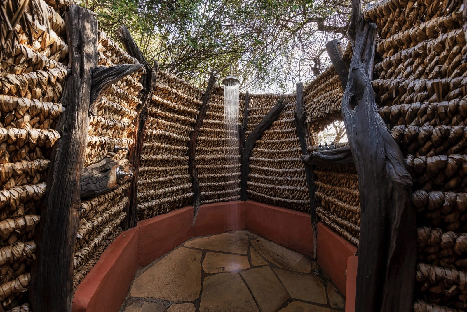 An open-air shower walled in woven branches